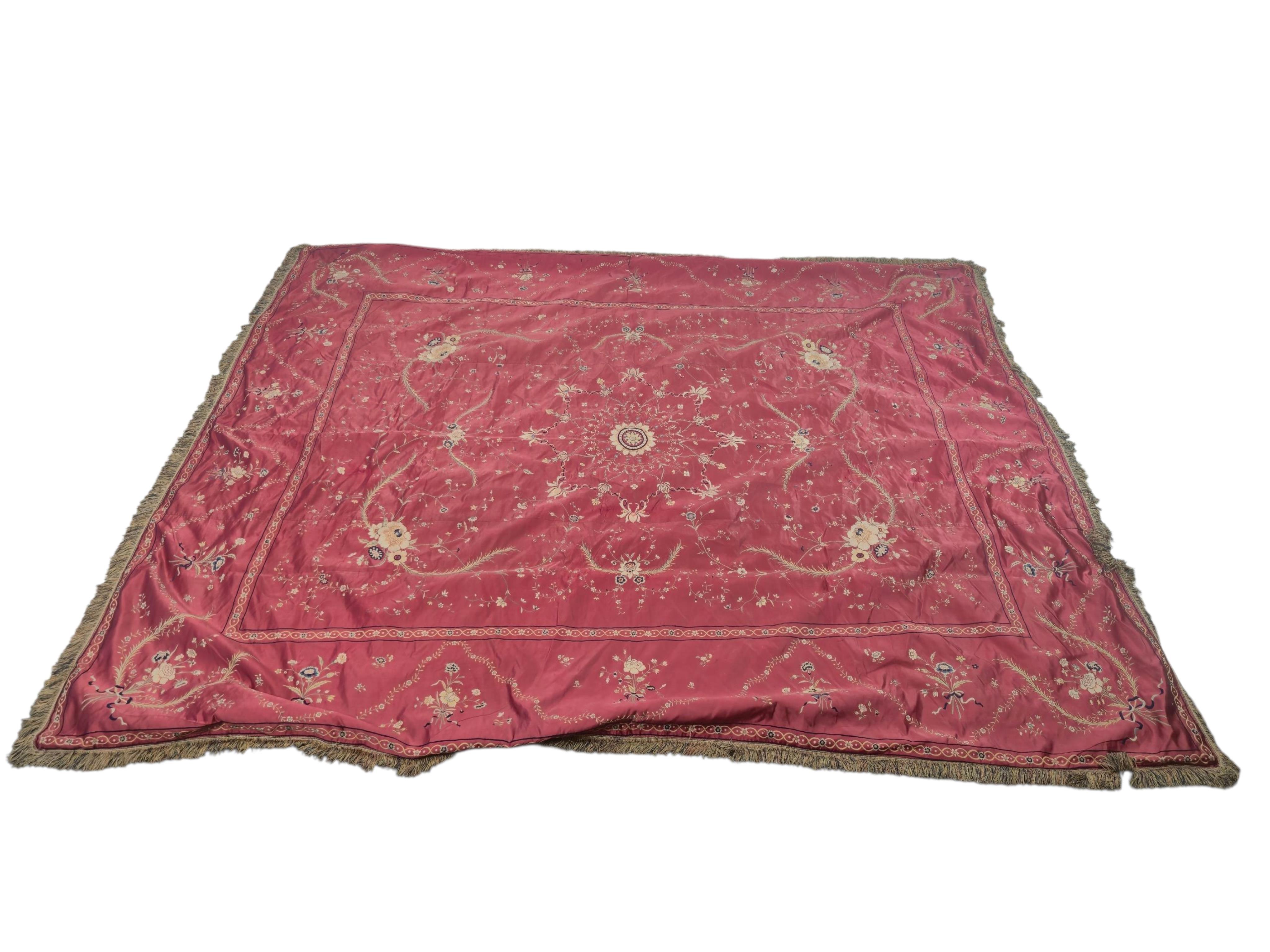 A Chinese 19th century Qing Dynasty crimson red silk embroidered hanging. Embroidered with sprays and swags of flowers and foliage, depicting prosperity and fortune, around a central stylistic sun motif, depicting perfec